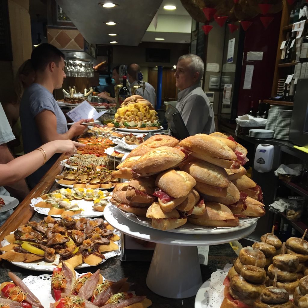 People browsing a bar of pintxos